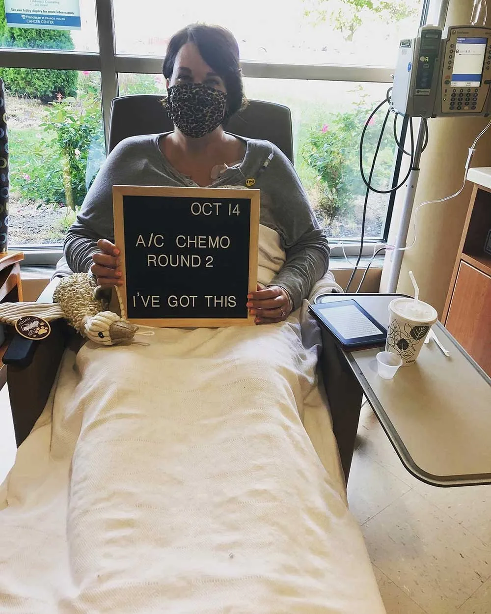 Amanda holding a letter board during chemotherapy