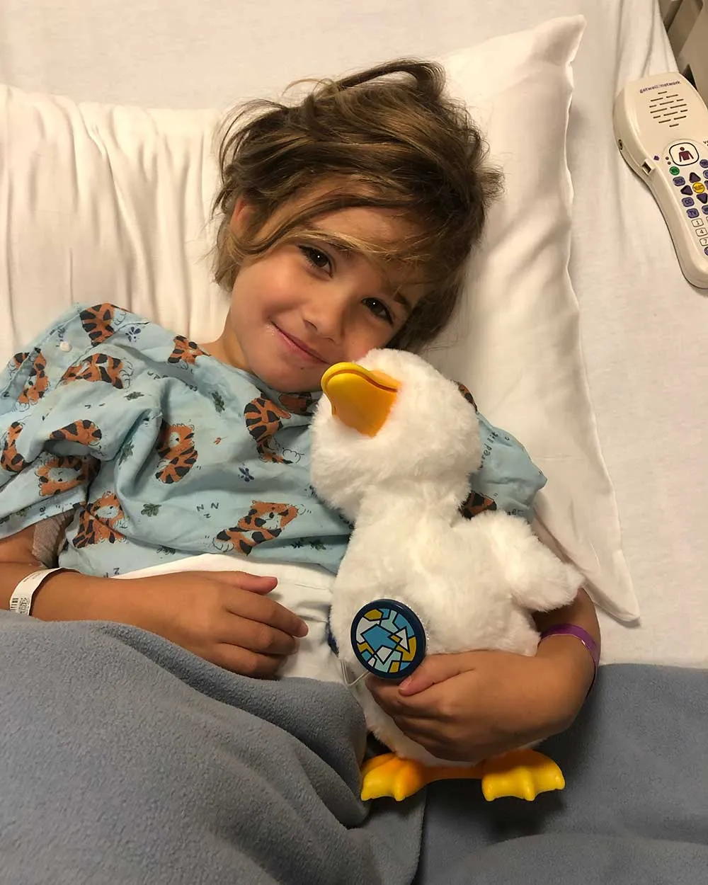 Isabel in her hospital bed hugging a stuffed duck