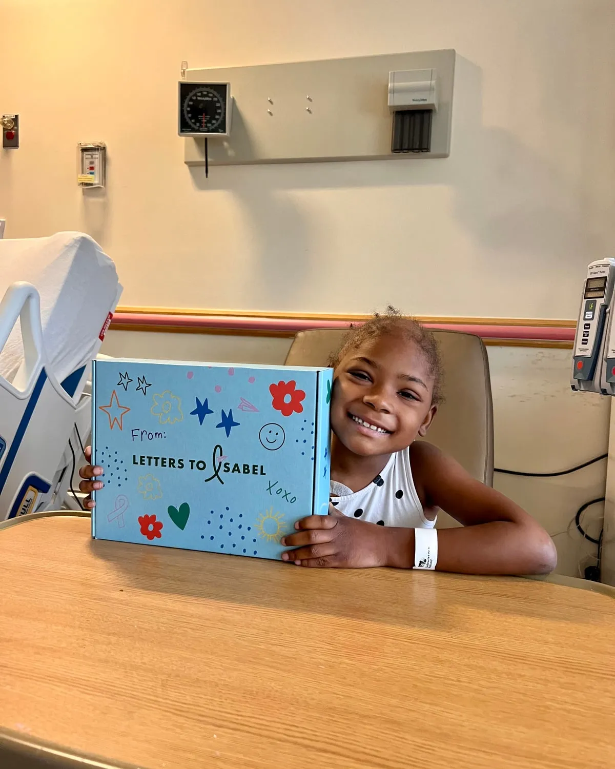 Smiling girl hugging her Boombox at a hospital tray table